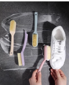Macro shot of 4 colorful plastic shoe brushes cleaning a white sneaker on dark tiles