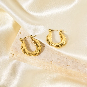 Dettaglio ravvicinato di orecchini a cerchio intrecciati placcati in oro 18K su pietra e seta