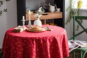 Close-up of red Christmas tablecloth with gold snowflake patterns on a dining table