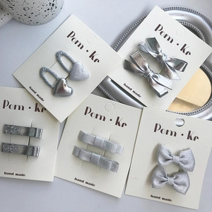 Silver bow hair clips and heart hair ties set on white display cards for children