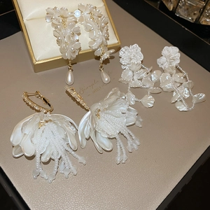Detailed macro of elegant floral tassel earrings with pearls and gold accents on a display