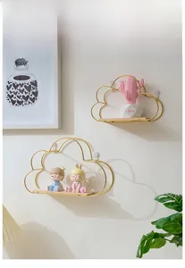 Detail of cloud-shaped iron wall shelf with gold finish and wooden base in Nordic style