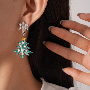 Detail view of a Christmas tree earring with green rhinestones and white pearls on a model