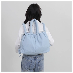 Detail of light blue puffy nylon backpack showing drawstring closure and soft texture
