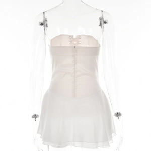 Detail of white mini dress featuring a lace-up back and ruffled hem on a clear mannequin