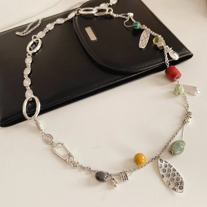 Detail of vintage necklace with colorful beads and metal pendants on black leather