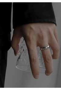 Close-up of silver Mobius ring with twisted metal texture on hand holding glass