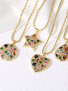 Macro detail of gold necklaces featuring heart and star pendants with colorful stones