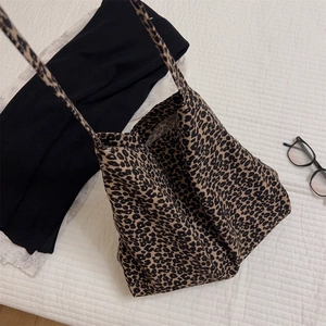 Vista piatta di una borsa tote in tela leopardata con spalline lunghe e dettagli neri