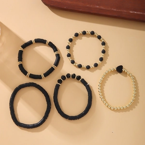 Detail view of five-piece black and gold stretch bracelet set with heart charms and beads