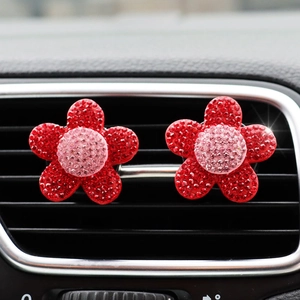 Macro shot of red rhinestone flower car air vent clips with pink centers on a car grille