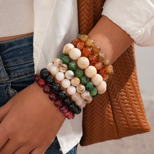 Stack of colorful acrylic beaded bracelets with marbled texture on model's wrist