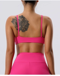 Detail of hot pink ribbed sports bra with thin straps and matching high-waisted yoga pants