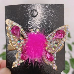 Macro detail of butterfly hair clip with pink crystal stones and golden wings
