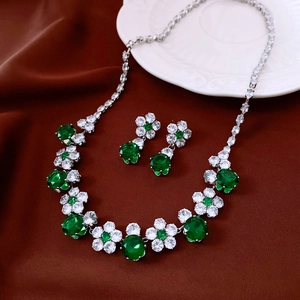 Close-up of vintage jewelry set with emerald zircon flowers on red silk fabric