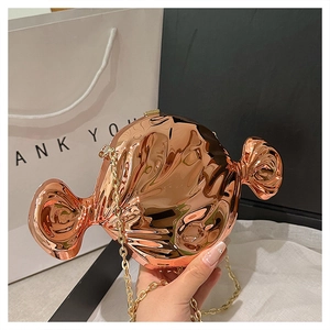 Detail of rose gold candy-shaped hard shell bag with shiny crinkle texture and gold chain