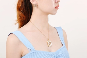 Detailed view of a gold-plated stainless steel necklace and C-shape shell earrings on a model