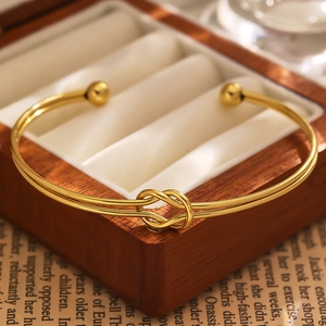 Detail of 18k gold plated stainless steel bracelet with a woven love knot design