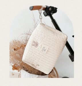 Close-up of quilted cream baby stroller bag with bear embroidery and side hanging hooks