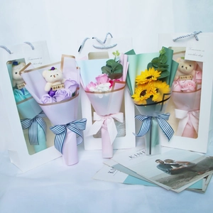 Close-up of handmade soap flower bouquets with sunflower and plush bear in gift bags