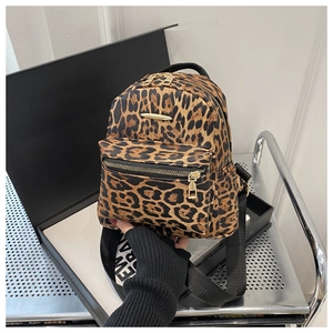 Detail of leopard print backpack featuring gold-tone zippers and lettered straps