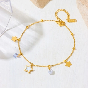 Detail view of gold stainless steel bracelet with star charms and zircon stones on white stone