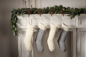 Macro detail of knitted Christmas stockings with fish scale patterns hanging on fireplace