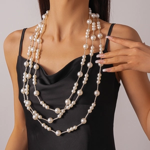 Gros plan d'un collier de perles à trois rangs avec détails argentés sur robe en soie