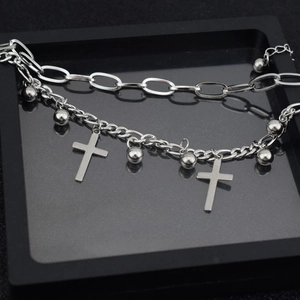 Double-layered stainless steel bracelet with cross and ball charms on a black display tray