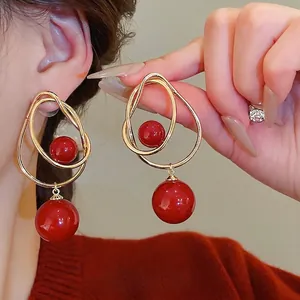 Boucles d'oreilles cercles entrelacés dorés avec perles rouges sur un mannequin
