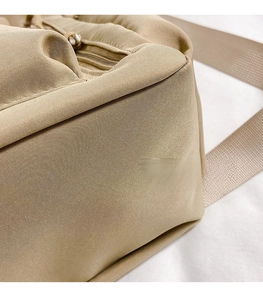 Close-up of durable khaki nylon fabric texture and reinforced strap of the shoulder bag