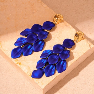 Detail of dark blue acrylic petal tassel earrings on a neutral stone background