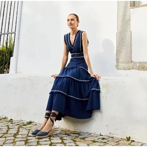 Détail d'une robe longue à volants bleu marine avec broderie et sandales compensées