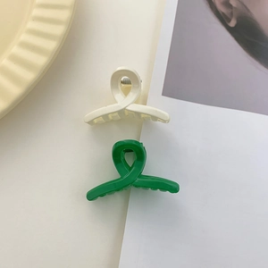 Detail view of mini matte hair clips in cream and green showing interlocking cross design