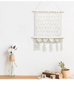 Détail d'une suspension murale bohème avec motifs de cœur et pompons en coton tissé