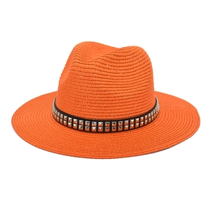 Detailed macro of orange straw fedora hat featuring black band with silver square studs