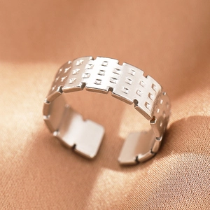 Macro view of silver stainless steel open ring with geometric patterns and textured edges