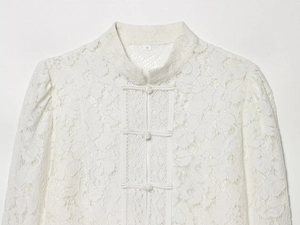Détail d'un haut en dentelle blanche avec col montant et boutons de style chinois