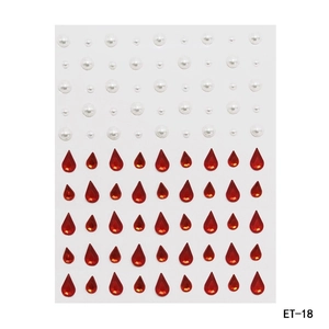 Macro detail of red teardrop rhinestones and white round pearls for DIY facial makeup art