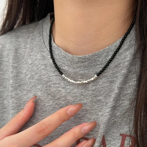 Minimalist black onyx beaded necklace with silver accents worn on a casual grey t-shirt