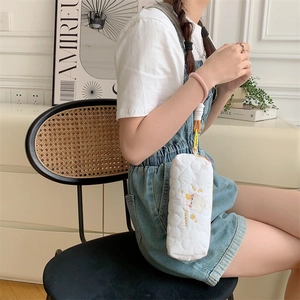 Quilted white pencil case with cute embroidery held by model in lifestyle setting