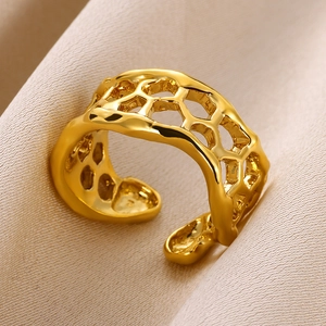 Macro view of gold lava texture ring with honeycomb cutouts on silk background