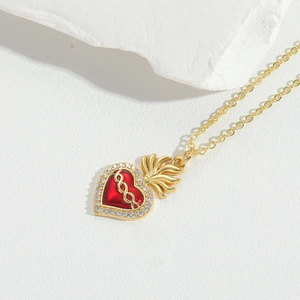Macro shot of red heart enamel pendant with white cubic zirconia and gold flame detail
