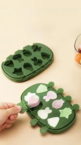 Detail of green silicone popsicle mold with 3D shapes like rabbits and strawberries