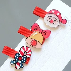Detail of Christmas hair clips set with Santa, bell and candy cane on red ribbon