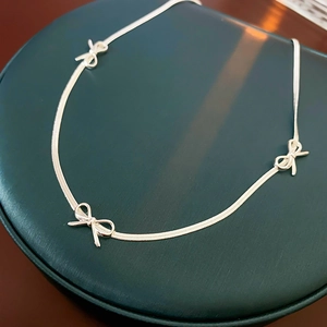 Detailed view of a stylish silver bow bracelet on a premium green display cushion