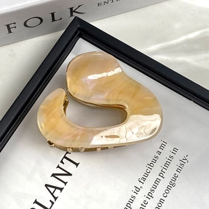 Detail of yellow marbled acetate hair claw clip with golden metal spring on a magazine