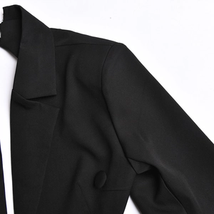Detailed view of black dress collar and shoulder with a decorative button and premium texture