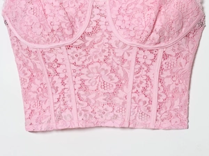 Close-up of pink lace crop top detailing floral patterns and structural seam stitching