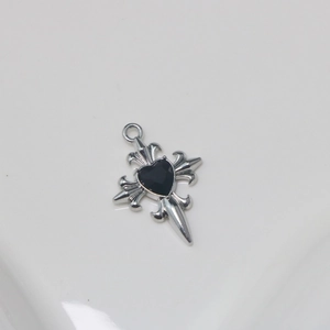 Detailed view of silver cross pendant with a black heart-shaped gemstone inlay